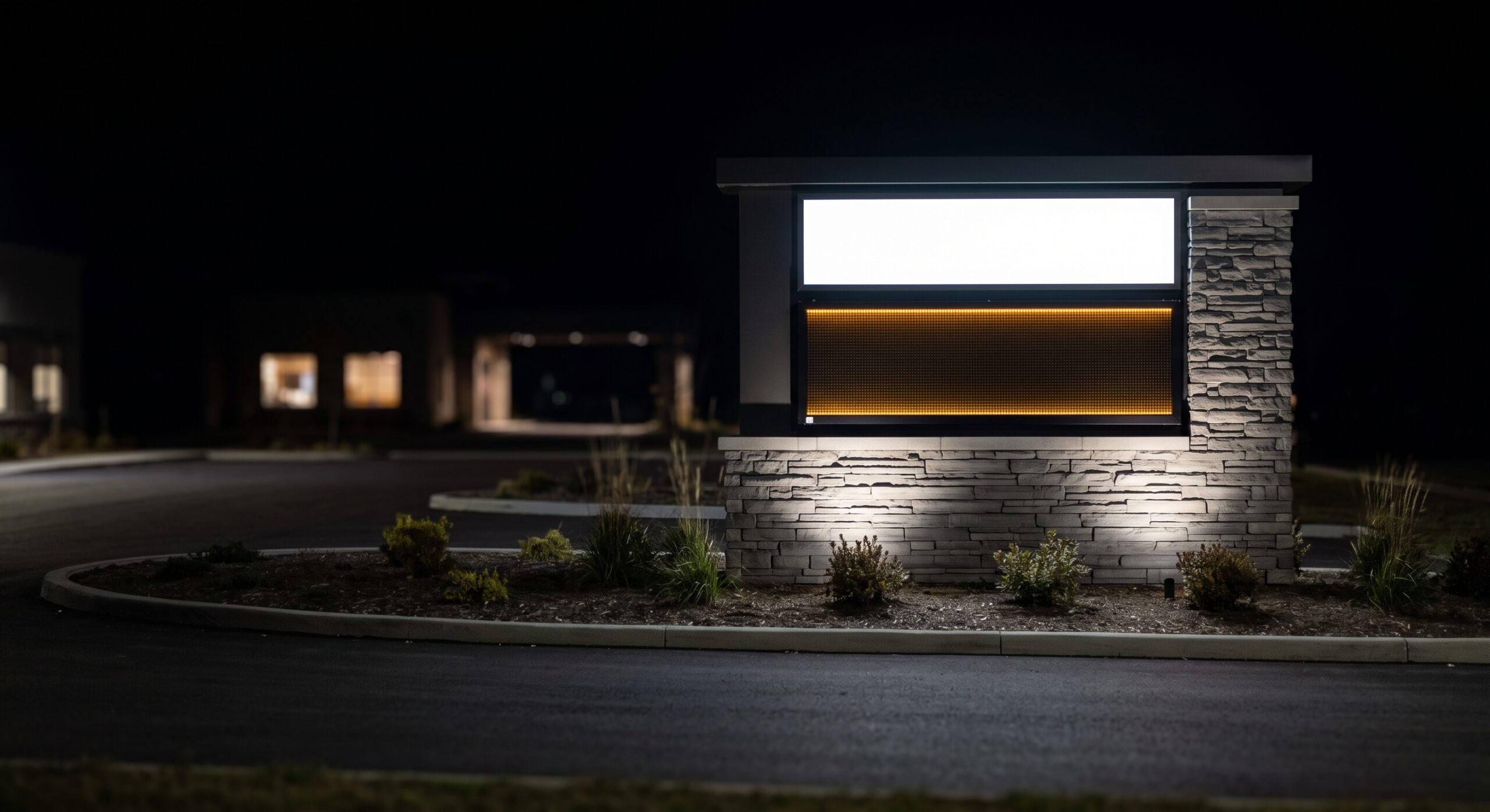 Low profile monument sign with an illuminated push-through panel and electronic reader board at night in Lewisville, Texas